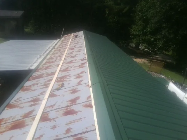 Old rusted panels beside newly installed green metal roofing — Wind Damage Roof Repair by Roofing Brothers in Eagle Creek