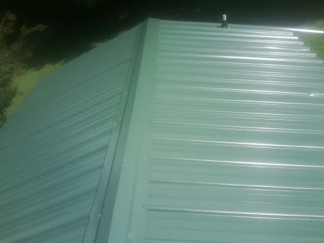 New green metal panels meeting at the ridge of a roof — Flat Roof Repair work by our crew in Eagle Creek