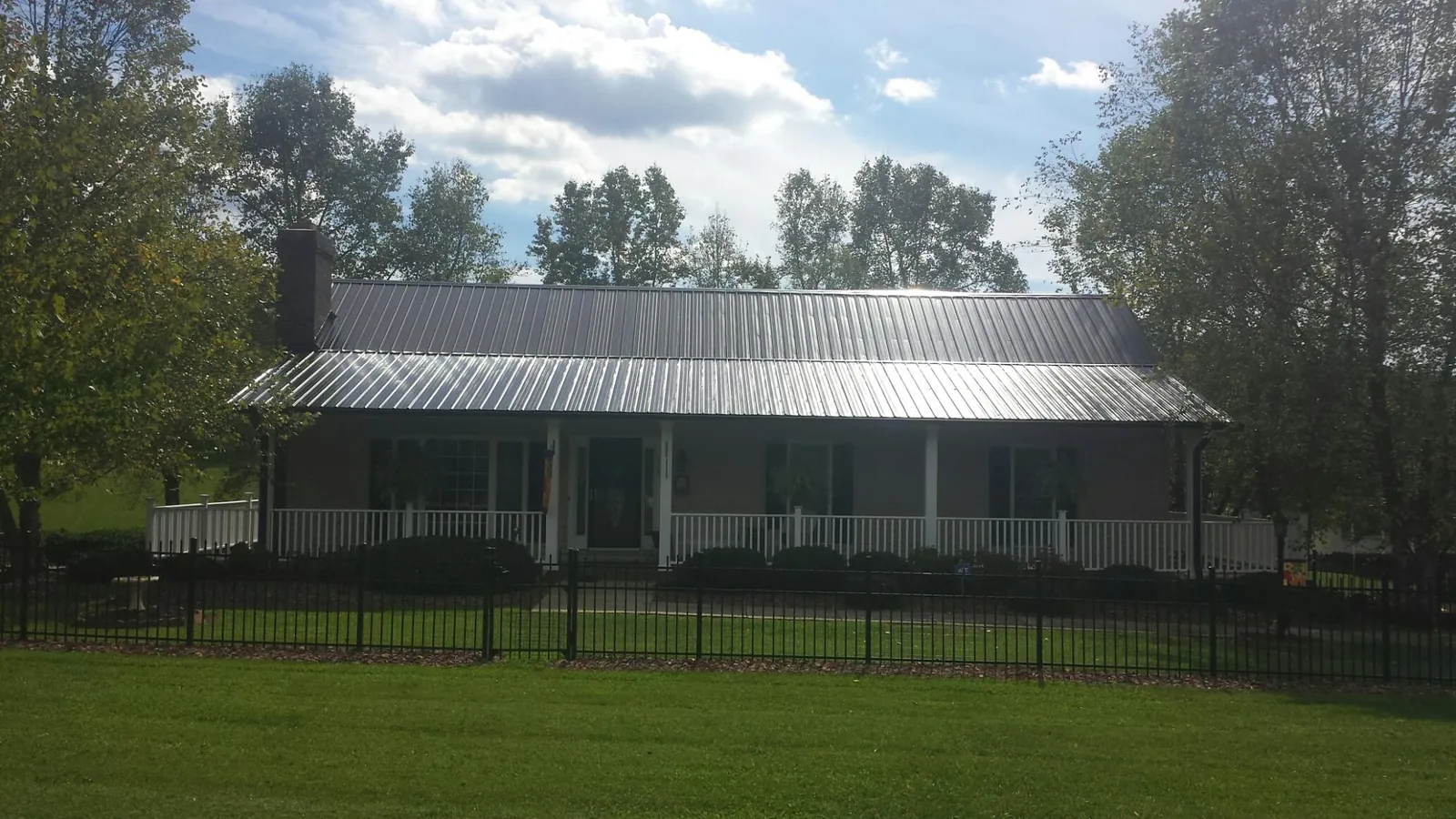 Gray metal roof on a brick ranch with a full width front porch — Gutter Guard Installation work by our crew in Eagle Creek