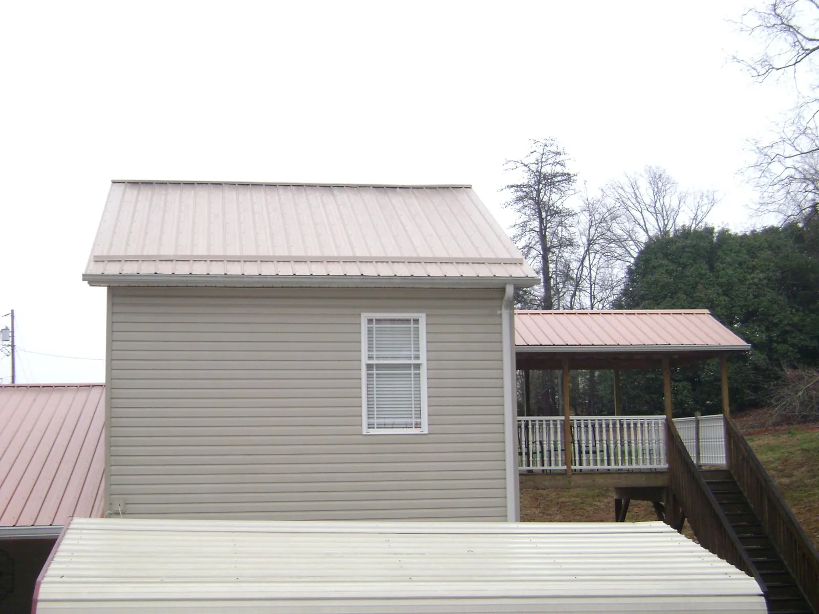 Tan metal roofs on a two story addition and attached porch, from a Roof Replacement job in Eagle Creek