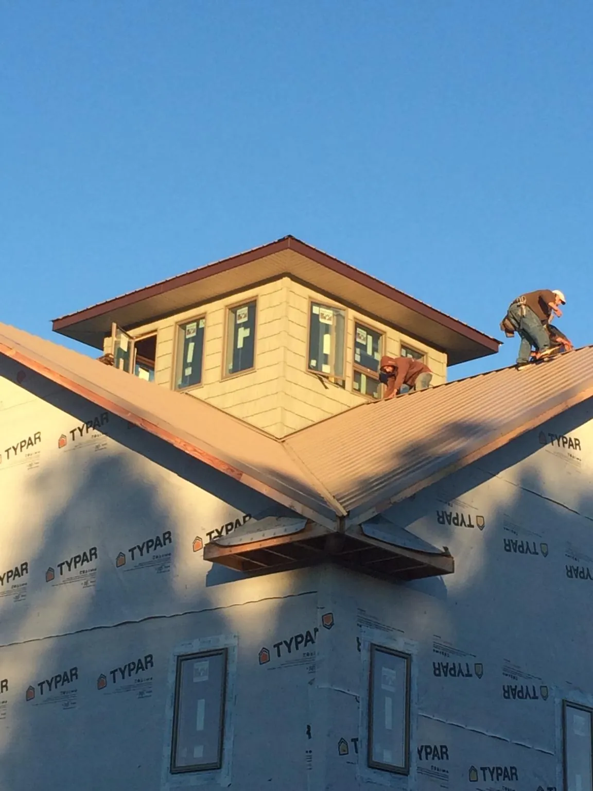Roofers working around a rooftop cupola on a new metal roof at sunset — Roof Waterproofing in Eagle Creek by Roofing Brothers
